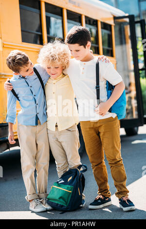 Glücklichen kleinen Schuljungen Ausgabe Zeit zusammen vor der Schule Bus Stockfoto