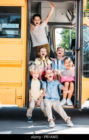 Gruppe von adorable Schulkinder sitzen auf der Treppe der Schulbus und Schreien Stockfoto