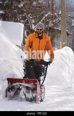 Mann mit Schneefräse Maschine in schneereichen Region Stockfoto