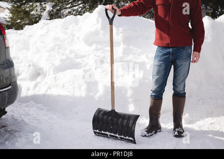 Mann mit schneeschaufel an einem verschneiten Region Stockfoto