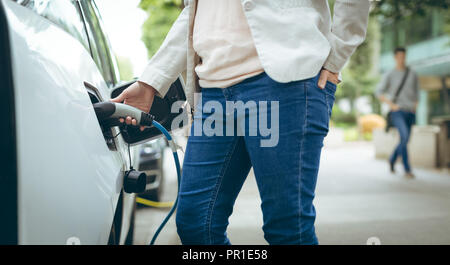 Geschäftsfrau laden Elektroauto an der Ladestation Stockfoto