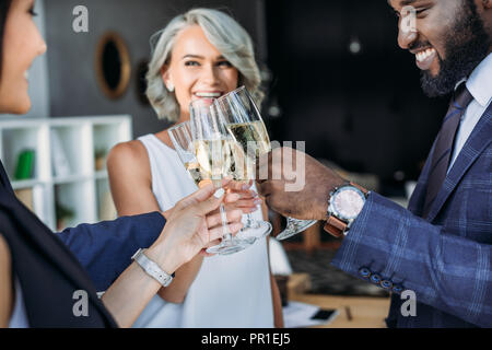 Lächelnd multiethnischen Geschäftsleute mit klirren Gläser Champagner in Office Stockfoto