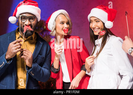 Fröhlich multikulturellen Geschäftsleute holding Lippen und Brille auf der Nase klebt am neuen Jahr Corporate Partei Stockfoto
