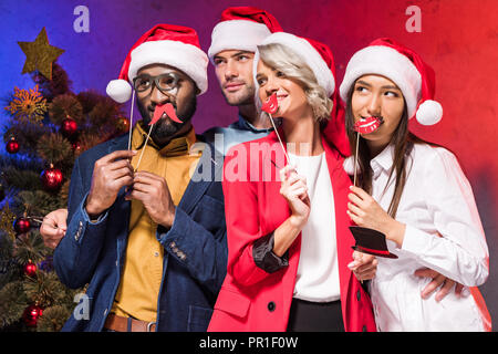 Multikulturelle Geschäftsleute holding Lippen und Brille auf der Nase klebt am neuen Jahr Corporate Partei und Wegsehen Stockfoto