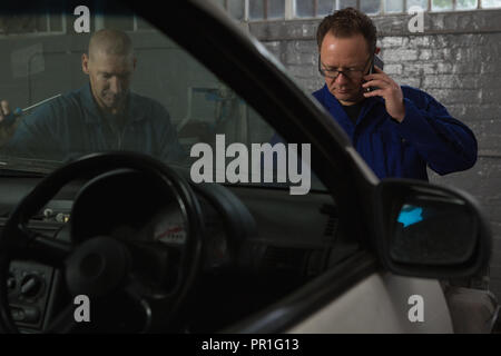 Männliche Mechaniker Gespräch am Handy Stockfoto