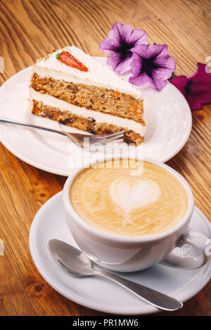 Tasse Cappuccino mit leckeres Stück Karottenkuchen auf dem hölzernen Tisch Stockfoto