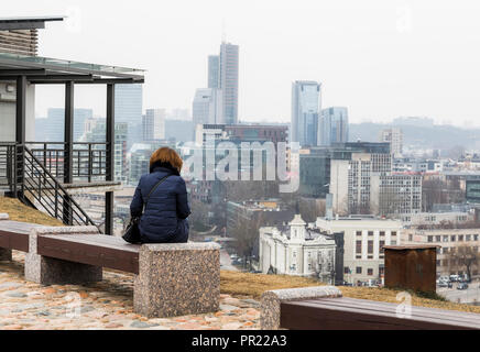 Ein Mädchen sitzt auf einer Bank auf der Aussichtsplattform im Turm von Gediminas an der Stadt, die in einer leichten Dunst. Vilnius. Litauen Stockfoto