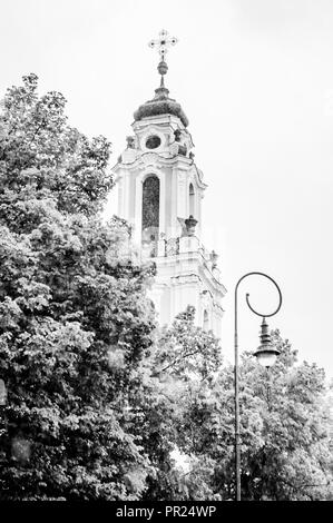 Vilnius, Litauen - 17. Mai 2014: Straßenlaterne, Baumkronen und einem oberen Teil der Turm der Kirche St. Katharina. Diese Kirche wurde erbaut im 17. Stockfoto