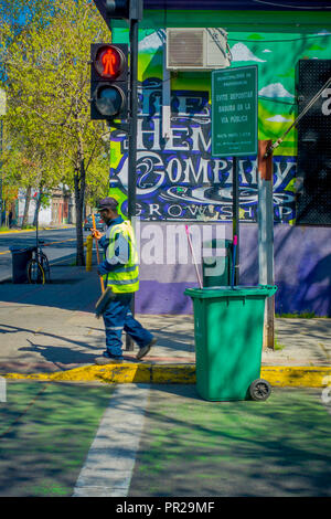 SANTIAGO, CHILE - 17. SEPTEMBER 2018: Im freien Blick auf unbekannter Mann tragen grüne Uniform und fegt die Straßen in der Nähe an einer roten Ampel in die Downtown der Stadt Santiago Stockfoto