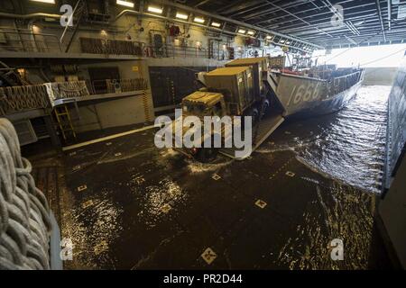 CORAL SEA (Juli 24, 2017) ein Marine Fahrzeug fährt Landing Craft utility 1666 in der gut Deck des amphibious Transport dock USS Green Bay LPD (20) Nach der Talisman Sabre 17. Talisman Säbel ist eine Biennale USA - Australien bilaterale Übung gehalten weg von der Küste von Australien gedacht, um die Interoperabilität zu erreichen und den USA - Australien Bündnis stärken. Stockfoto