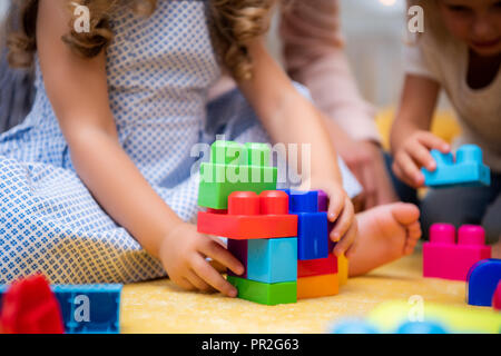 Zugeschnittenes Bild der Kinder spielen mit Kunststoff farbig Konstruktor im Kindergarten Stockfoto