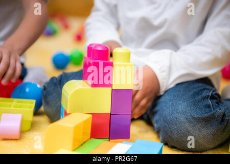 Zugeschnittenes Bild der afrikanischen amerikanischen Jungen spielen mit Kunststoff Konstruktor im Kindergarten Stockfoto