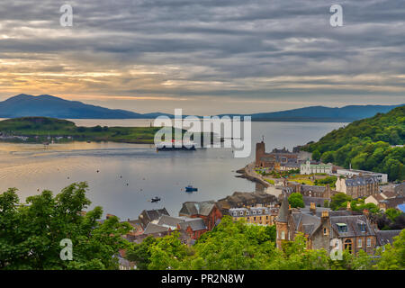 Moody's Blick von einem Hügel in der Hafenstadt Oban, Schottland mit Blick auf die Stadt und das Wasser mit der Isle of Mull in der Ferne mit einem Hauch von Stockfoto