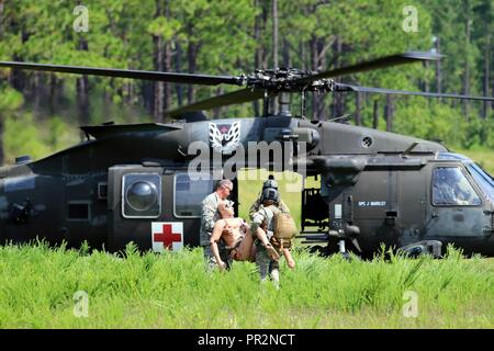 Einen Flug medic zu 3-82 nd Allgemeine Unterstützung Aviation Battalion, 82nd Combat Aviation Brigade, 82nd Airborne Division, und ein Beobachter-Controller einen simulierten Unfall ein UH-60 Blackhawk Hubschrauber für medizinische Evakuierung im Notfall Szenario in Fort Bragg, North Carolina, 25. Juli 2017. Das Szenario Ersthelfer von Fort Bragg Feuerwehr- und Rettungsdienste, Militär, Polizei und dem 82Nd CAB koordiniert. Stockfoto