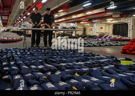 BREMERTON, Washington (25 Juli 2017) Seaman Rachel Cervantes, Links, aus Miami, und Seaman Hongjie Chen, aus New York, ersetzen Sie die Batterien auf aufblasbaren Leben Lichtformen im Vorschiff der Flugzeugträger USS John C Stennis (CVN 74). John C Stennis führt eine geplante schrittweise Verfügbarkeit Puget Sound Naval Shipyard und Intermediate Maintenance Facility, die sich einer geplanten Wartung und Upgrades. Stockfoto