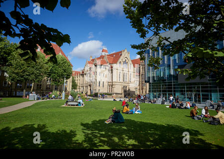 Schüler entspannen auf dem Gras Parks um Manchester Oxford Road Alan Gilbert Learning Commons und Whitworth Hall, Christie's Bistro net-gotischen Buil Stockfoto