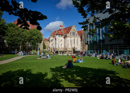 Schüler entspannen auf dem Gras Parks um Manchester Oxford Road Alan Gilbert Learning Commons und Whitworth Hall, Christie's Bistro net-gotischen Buil Stockfoto