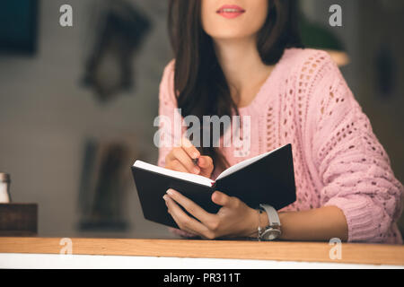 Teilweise mit Blick auf die Frau, die Noten im Lehrbuch am Tisch im Cafe Stockfoto