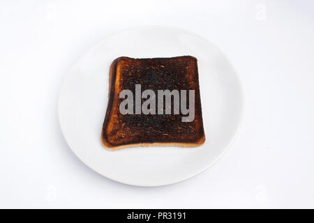 Burnt Toast liegt auf einem weißen Teller auf weißem Hintergrund Stockfoto