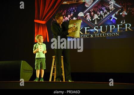 Mike Super, Illusionist, führt eine Card Trick mit der Unterstützung von Jackson Hedin, Sohn von Maj Cory Hedin, 81st Diagnostik und Therapeutik Squadron Apotheke Operations Chief, während des Mike Super Magic & Illusion zeigen, in welch Theater Juli 29, 2017, auf Keesler Air Force Base, Fräulein Super, ein amerikanischer Magier, ist der Gewinner des NBC-show Phänomen, ist derzeit in den USA und Kanada mit seiner Illusion zeigen. Stockfoto