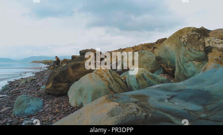 Junge Frau auf den Felsen an der Westküste von Irland sitzen Stockfoto