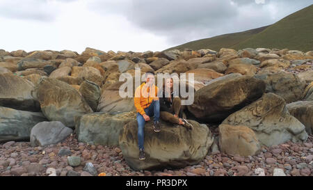 Paar auf den Felsen an der Westküste von Irland sitzen Stockfoto