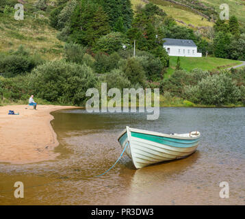 Ein einsamer Fischer und ein Boot am Strand von Lough Nafooey in der Region Connemara County Galway in Irland. Stockfoto