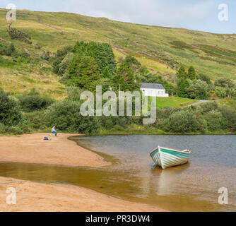 Ein einsamer Fischer und ein Boot am Strand von Lough Nafooey in der Region Connemara County Galway in Irland. Stockfoto