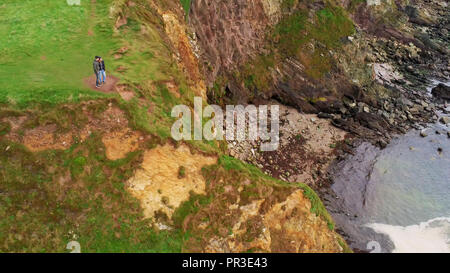 Paar steht am Rande von Dunquin Pier auf der Halbinsel Dingle - Luftbild Stockfoto