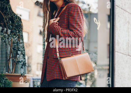 Street Style, attraktive Frau trägt einen Minirock, Check plaid Blazer und eine Leder braun Tragetasche. Fashion Outfit perfekt für den Herbst. Stockfoto