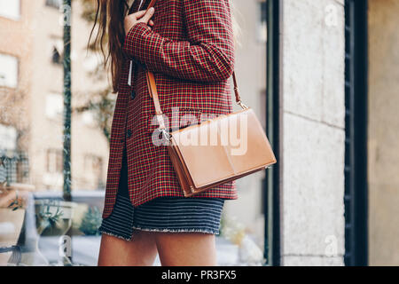 Street Style, attraktive Frau trägt einen Minirock, Check plaid Blazer und eine Leder braun Tragetasche. Fashion Outfit perfekt für den Herbst. Stockfoto