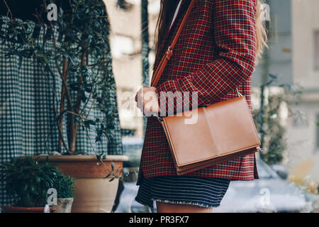 Street Style, attraktive Frau trägt einen Minirock, Check plaid Blazer und eine Leder braun Tragetasche. Fashion Outfit perfekt für den Herbst. Stockfoto