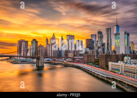 New York, New York, USA Lower Manhattan Skyline über den East River und die Brooklyn Bridge nach Sonnenuntergang.