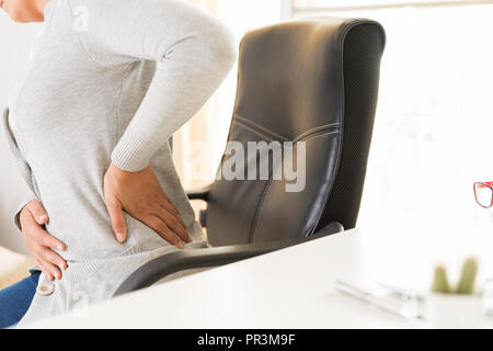 Closeup Frau mit Händen ihre Rückenschmerzen Holding. Office-Syndrom und Health Care Konzept. Stockfoto
