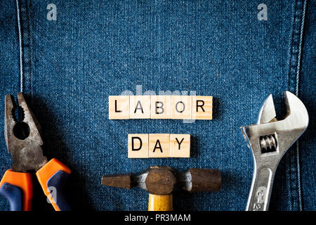 USA Tag der Arbeit, erster Montag im September. Verschiedene Arten auf Schlüssel, praktische Tools, Amerika Flagge und Holz- tag auf Blue Jeans Hintergrund. Stockfoto