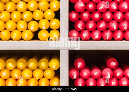 Rot und Gelb paraffin stick Kerzen auf Regalen in einem Shop angeordnet Stockfoto