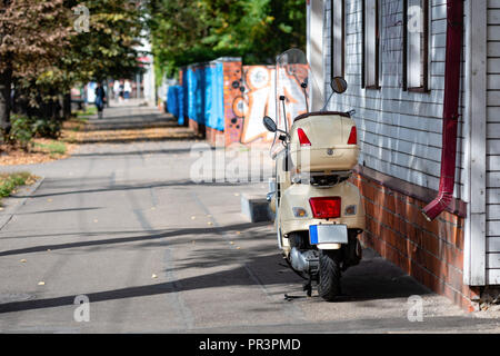 Ein Roller ist an der hölzernen Gebäude in der Nähe der Straße. Stockfoto