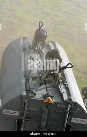 Drei US-Soldaten aus einem multi-role Brücke Unternehmen knien auf eine verbesserte Ribbon Bridge (IRB) Bay Abschnitt an eine CH-47 Chinook von Unternehmen B, 7 (Allgemeine Luftfahrt) Bataillon, 158 Aviation Regiment, im Aviation Brigade, Armee-reserve Aviation Befehl während der Fluss Angriff 2017 auf Fort Chaffee Manövrieren Training Center, 26. Juli 2017 warten. Die Chinook fiel weg von der Bucht in den Arkansas River, um für den IRB-Ansatz über den Fluss gebaut werden, der Höhepunkt des Flusses angriff. Betrieb River Assault ist eine der wichtigsten Veranstaltungen, die zeigt, Stockfoto