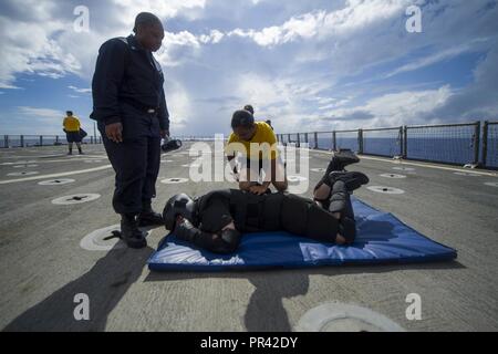 Pazifik (28. Juli 2017) Der Bootsmann Mate 2. Klasse Anuradha Figueroa, ein Eingeborener von Queens, New York, zu dem Deck Abteilung zugewiesen an Bord der Amphibischen dock Landung Schiff USS Pearl Harbor (LSD 52), Praktiken ein mock Takedown auf Senior Chief kulinarische Spezialist Garrett Richards, ein Eingeborener von Salem, Oregon, Supply Abteilung von Pearl Harbor zugewiesen wird, während eine Sicherheit Eingreiftruppe Training auf dem Schiff Flight Deck. Pearl Harbor, Teil der Amerika Amphibious Ready Group, mit 15 Marine Expeditionary Unit eingeleitet, in der pazifischen Region Indo-Asia p stärken Stockfoto