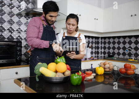 Glücklich und lächelnd junges paar Kochen in der Küche zu Hause. Stockfoto