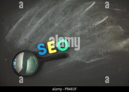 SEO Suchmaschinen Optimierung Konzept Farbe Buchstaben von SEO mit Lupe auf einem schwarzen Hintergrund Copyspace