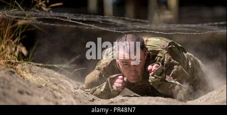 Sgt. Robert Sprott drückt sich durch Wolken von Staub, wie er unter Stacheldraht kriecht - Leitung während der 2017 Madigan Army Medical Center Best Medic Wettbewerb im Joint Base Lewis-McChord, Tacoma WA. Stockfoto