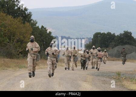 Us Soldaten vom 1. gepanzerte Brigade Combat Team, 1.Kavallerie Division, laufen beim Tragen von Schutzanzügen während der CBRN (chemische, biologische, radiologische und nukleare Verteidigung) Lane einer Spur fahren, Novo Selo, Sept. 7, 2018. Der Sporn Fahrt ist eine altehrwürdige Tradition, die Kavallerie Kavallerie Truppen die Möglichkeit, Silber zu erwerben Sporen durch die Teilnahme an einer Reihe von körperlichen und geistigen Herausforderungen, die hilft, die Kameradschaft erstellen und bauen Esprit de Corps. Stockfoto