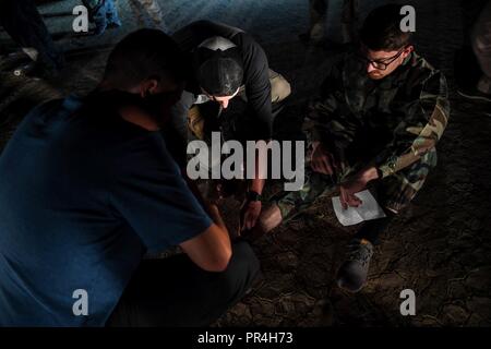 Us Army Combat Medics, die auf das 10. Berg Geschäftsbereich zugeordnet sind, moulage zu einem simulierten Unfall gelten während einer Messe Unfallversicherung Übung im Grand Bara Wüste, Dschibuti, Sept. 10, 2018. Die Übung ist so konzipiert, dass der Service Mitglieder Opfer in chaotischen Situationen zu behandeln vorbereiten, während die zusammen arbeiten. Stockfoto