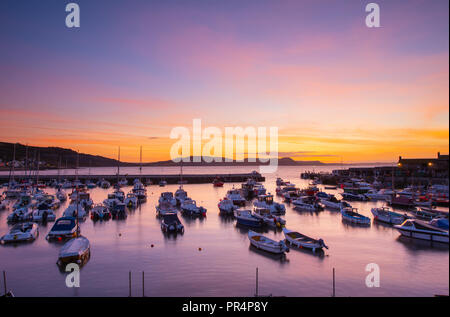 Lyme Regis, Dorset, Großbritannien. 29. September 2018. UK Wetter: der Himmel über dem Cobb Hafen glühen mit leuchtenden Farben zu Beginn eines sonnigen Tages in Lyme Regis. Credit: Celia McMahon/Alamy leben Nachrichten Stockfoto