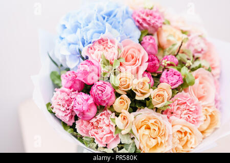 Schöner Frühling Bouquet. Blumen Anordnung mit verschiedenen Farben in Glas Vase auf rosa Tabelle. Helles Zimmer, weiße Wand. Stockfoto