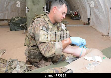 MAJ Kenneth Reed, 44. Medizinische Brigade, Preps ein IV auf seinem Teamkollegen 1 LT Tyler Martin zu verwalten. Stockfoto