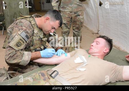 MAJ Kenneth Reed, 44. Medizinische Brigade, Preps ein IV auf seinem Teamkollegen 1 LT Tyler Martin zu verwalten. Stockfoto