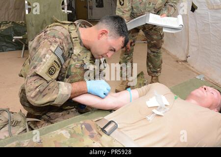 MAJ Kenneth Reed, 44. Medizinische Brigade, Preps ein IV auf seinem Teamkollegen 1 LT Tyler Martin zu verwalten. Stockfoto