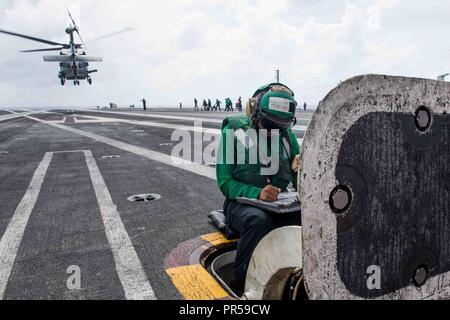 Philippinischen MEER (18. September 2018) der Luftfahrt Bootsmann Mate (Ausrüstung) Airman Kiara Webb, von Houston, führt vor, wie einem MH-60R Sea Hawk zu Hubschrauber Maritime Strike Squadron (HSM) 77 zugewiesen ist, aus dem Flight Deck der Marine vorwärts - bereitgestellt Flugzeugträger USS Ronald Reagan (CVN 76) Während der Valiant Shield 2018. Das zweijährige, nur in den USA, Ausbildung Übung konzentriert sich auf die Integration der gemeinsamen Ausbildung von der US Navy, Air Force und Marine Corps. Dies ist der siebte Übung in der Valiant Shield-Serie, die 2006 begann. Stockfoto